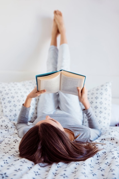 Kostenloses Foto lesung der jungen frau auf bett