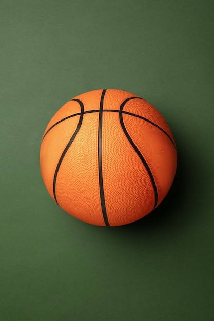 Leuchtender orange-brauner Basketballball. Professionelle Sportausrüstung lokalisiert auf grünem Hintergrund.