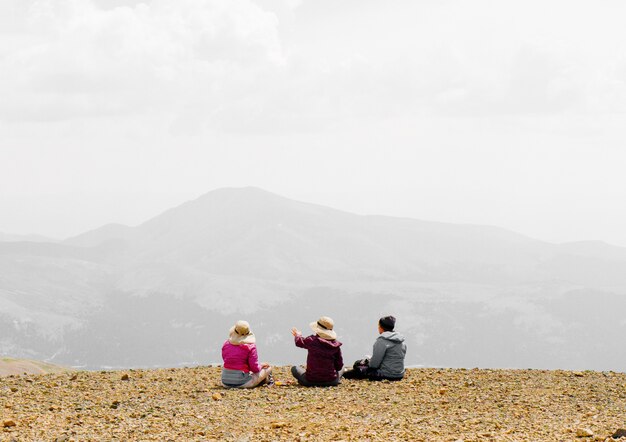 Leute, die am Rande des Berges sitzen und die Aussicht genießen und mit einem nebligen Hintergrund sprechen