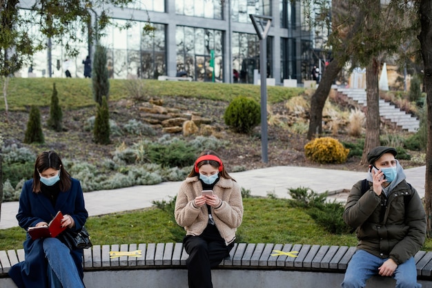 Kostenloses Foto leute, die auf distanz sitzen und maske tragen