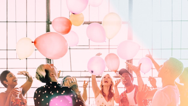 Leute, die auf einer Partytapete mit Luftballons spielen