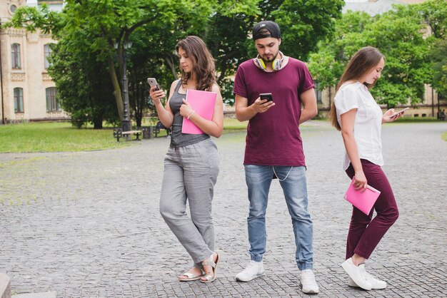 Leute, die auf Smartphones stehen, die draußen stehen