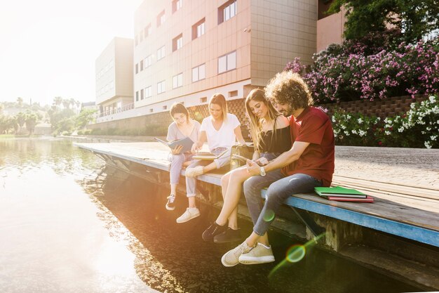 Leute, die das Sitzen nahe Wasser studieren