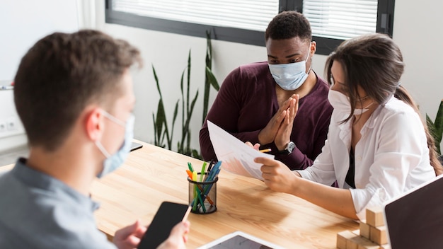 Leute, die im Büro während der Pandemie mit Masken arbeiten