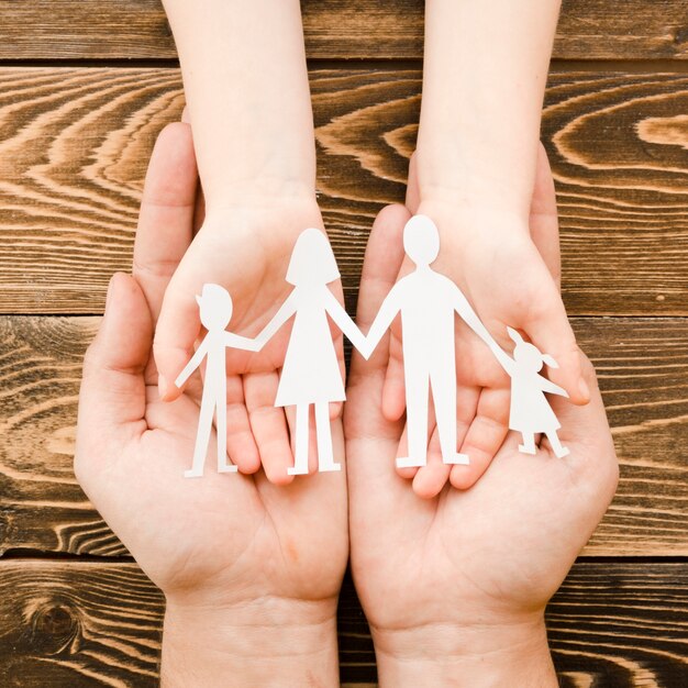 Leute, die Papierfamilie auf hölzernem Hintergrund halten
