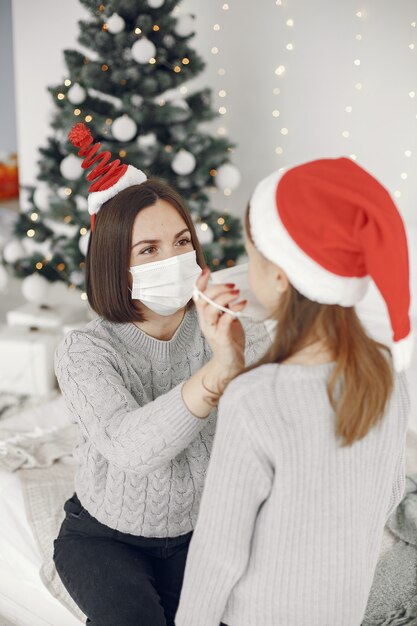 Leute, die sich auf Weihnachten vorbereiten. Coronavirus-Thema. Mutter spielt mit ihrer Tochter. Kind in einem grauen Pullover.