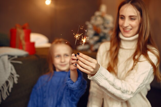 Leute, die sich auf Weihnachten vorbereiten. Kind mit bengalischen Lichtern. Die Familie ruht sich in einem festlichen Raum aus. Kind in einem blauen Pullover.