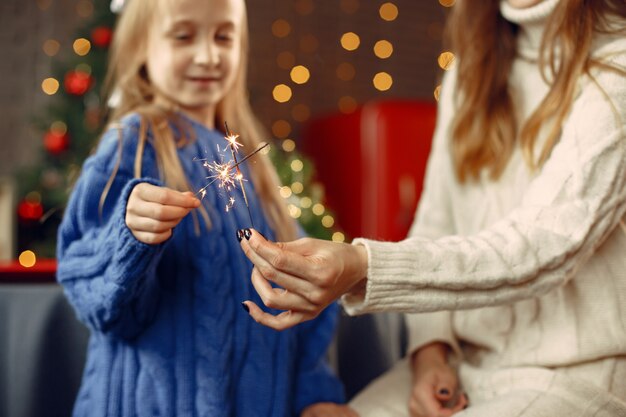 Leute, die sich auf Weihnachten vorbereiten. Kind mit bengalischen Lichtern. Die Familie ruht sich in einem festlichen Raum aus. Kind in einem blauen Pullover.