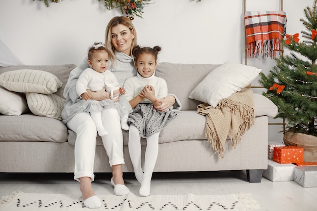 Kostenloses Foto leute, die sich auf weihnachten vorbereiten. mutter spielt mit ihren töchtern. die familie ruht sich in einem festlichen raum aus. kind in einem pullover pullover.