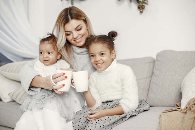 Leute, die sich auf Weihnachten vorbereiten. Mutter spielt mit ihren Töchtern. Die Familie ruht sich in einem festlichen Raum aus. Kind in einem Pullover Pullover.