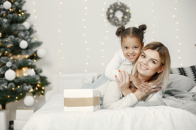 Leute, die sich auf Weihnachten vorbereiten. Mutter spielt mit ihrer Tochter. Die Familie ruht sich in einem festlichen Raum aus. Kind in einem Pullover Pullover.