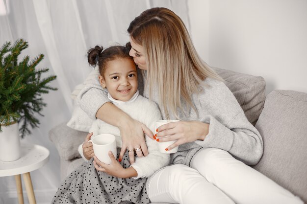 Leute, die sich auf Weihnachten vorbereiten. Mutter spielt mit ihrer Tochter. Die Familie ruht sich in einem festlichen Raum aus. Kind in einem Pullover Pullover.