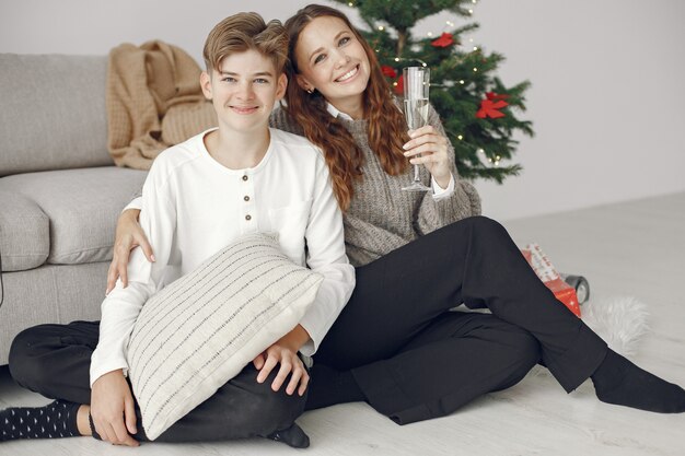 Leute, die sich auf Weihnachten vorbereiten. Mutter steht mit ihrem Sohn. Die Familie ruht sich in einem festlichen Raum aus. Menschen mit Champagner und Wunderkerzen.