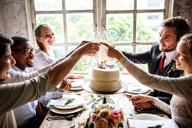 Leute, die Wein-Gläser auf Hochzeitsempfang mit Braut und Bräutigam klammern