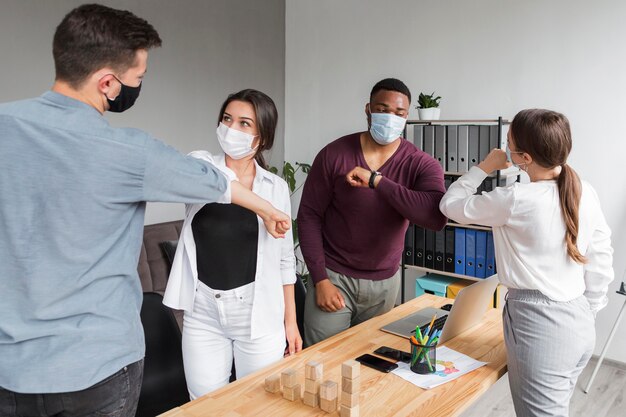 Leute im Büro während der Pandemie, die ein Treffen haben und Ellbogen berühren