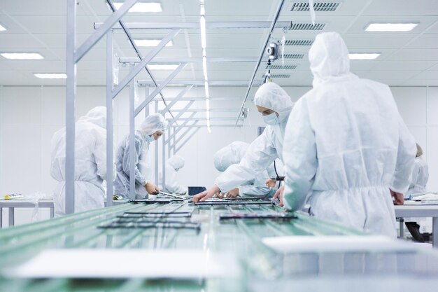 Leute in den weißen Isolierkostümen, die im Labor arbeiten