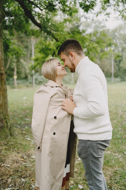 Leute in einem park. frau in einem braunen mantel. mann in einem weißen pullover.