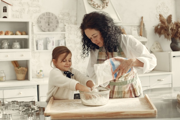 Leute in einer Küche. Großmutter mit kleiner Tochter. Erwachsene Frau lehren kleines Mädchen zu kochen.