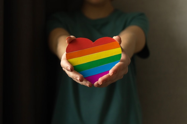 Lgbt-flagge, hände mit herz in regenbogenfarben, liebessymbol. konzept der homosexualität, lesben und schwulen, toleranz, preismonatsfoto