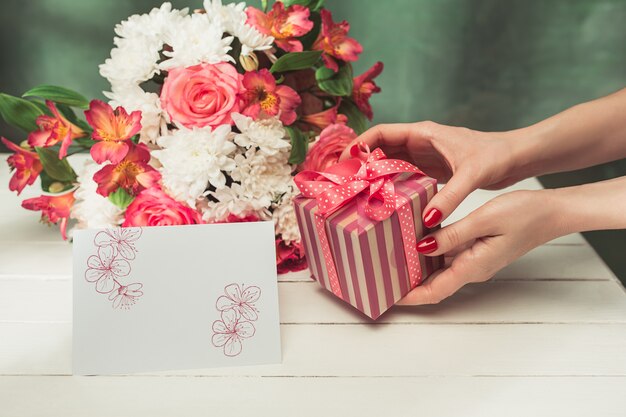 Liebeshintergrund mit rosa Rosen, Blumen, Geschenk auf Tisch