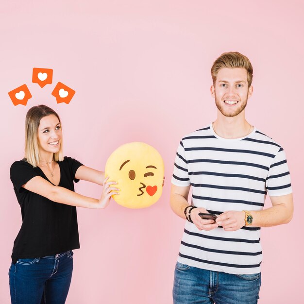 Liebesikonen über der glücklichen Frau, die Kuss emoji nahe ihrem Freund hält