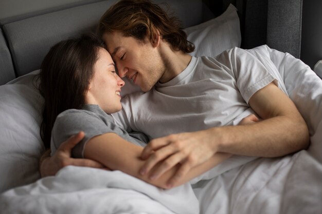 Liebevoll umarmende Paare während im Bett