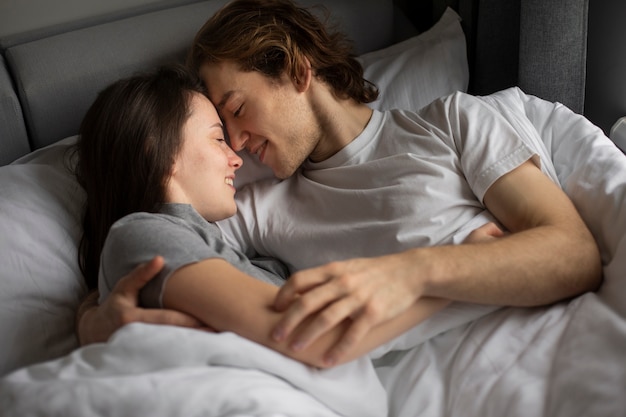 Liebevoll umarmende Paare während im Bett