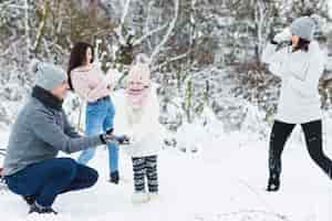 Kostenloses Foto liebevolle familie, die schneebälle in der landschaft spielt