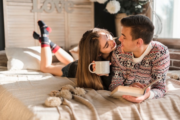 Kostenloses Foto liebevolle junge paare, die auf dem bett betrachtet einander liegen