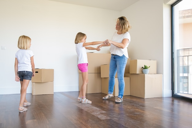 Liebevolle Mutter, die Spaß hat und mit der Tochter im Vorschulalter in einem neuen Zuhause tanzt