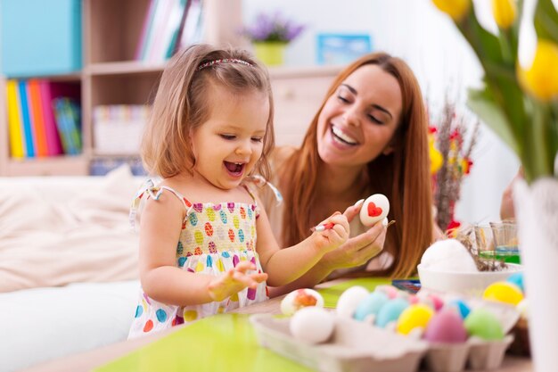 Liebevolle Mutter und ihr Baby malen Ostereier