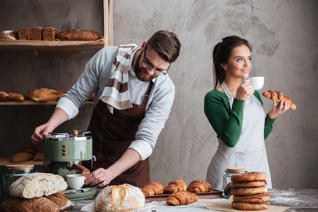 Liebevolle paar bäcker essen croissants, die kaffee trinken