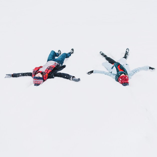 Liebevolle Paare, die im Schnee hat Spaß liegen