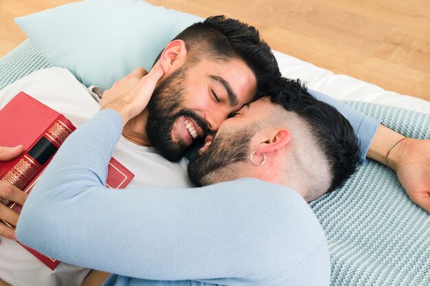 Liebevolle romantische junge homosexuelle Paare, die auf Bett liegen