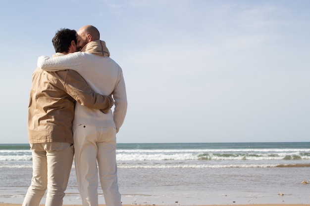 Liebevolle Schwule, die sich am Strand umarmen