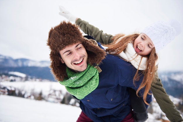 Liebevoller Vater, der Tochter huckepack trägt