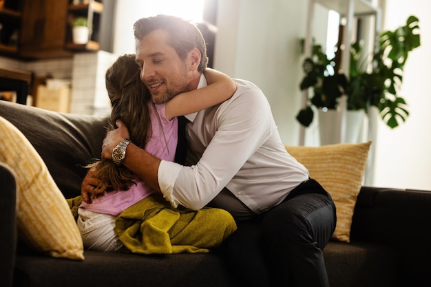 Liebevoller Vater und Tochter, die sich liebevoll im Wohnzimmer umarmen