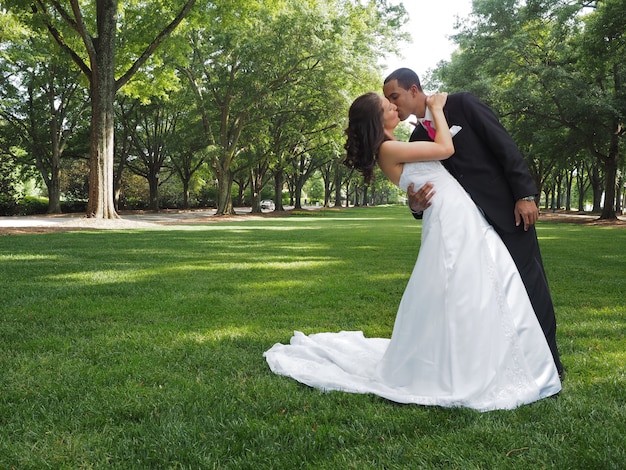 Liebevolles Ehepaar, das sich in einem grünen Park voller Bäume küsst