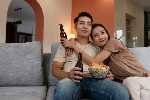 Liebevolles Paar zu Hause, das Essen in Schüssel und Bier isst