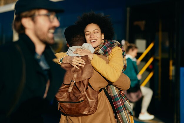 Liebevolles schwarzes Paar umarmt sich beim Gruß am Busbahnhof