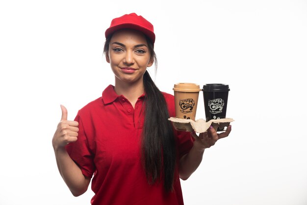 Lieferangestellte Frau in roter Mütze mit zwei Tassen Kaffee