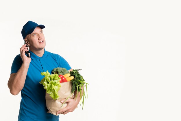 Lieferbote am Telefon mit Einkaufstüte in der Hand