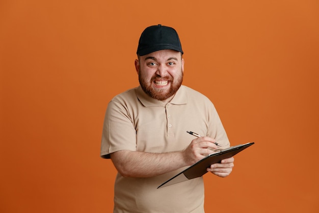 Lieferbote-Angestellter in schwarzer Mütze und leerer T-Shirt-Uniform hält Klemmbrett mit Stift und wartet auf eine Unterschrift, die genervt und wütend in die Kamera blickt und über orangefarbenem Hintergrund steht