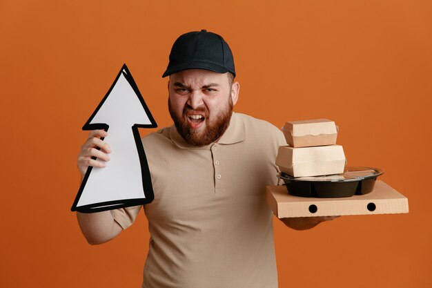 Lieferbote-Angestellter in schwarzer Mütze und leerer T-Shirt-Uniform mit Pfeil und Lebensmittelbehältern, die mit wütendem Gesicht auf orangefarbenem Hintergrund in die Kamera blicken