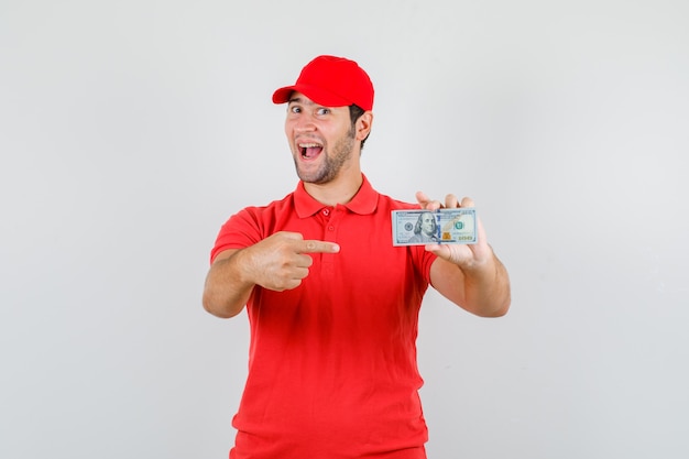 Lieferbote, der auf Dollarbanknote im roten T-Shirt zeigt