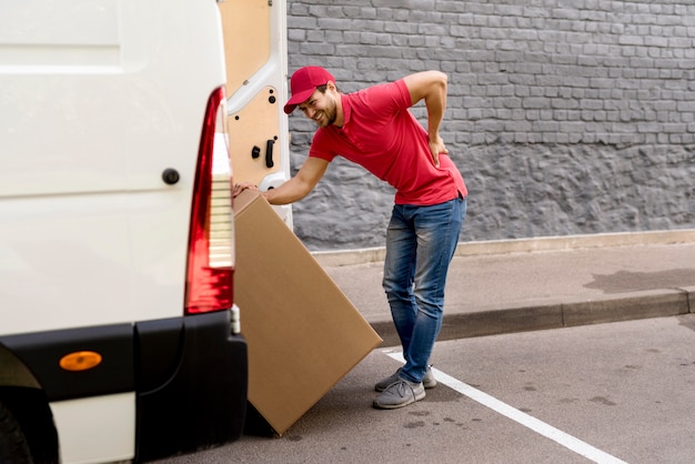 Lieferbote, der Auto mit Paket lädt