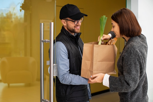 Kostenloses Foto lieferbote, der dem kunden lebensmittel bestellt