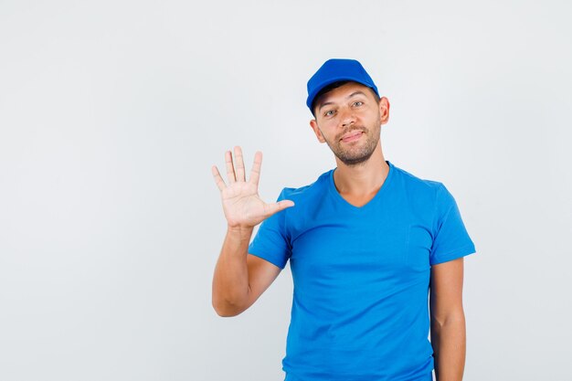 Lieferbote, der Handfläche im blauen T-Shirt zeigt