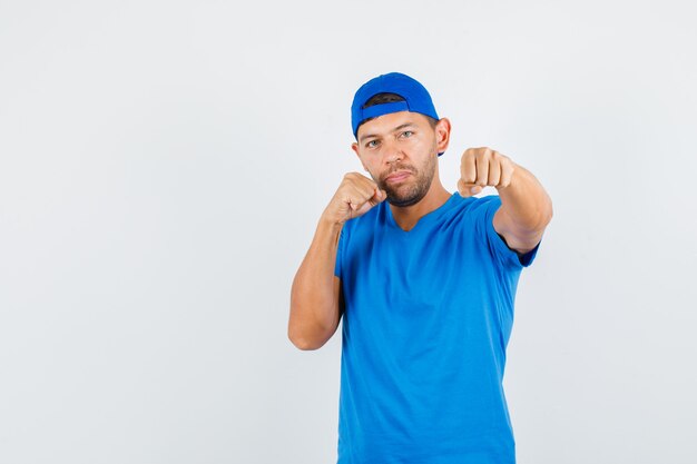 Lieferbote, der in der Boxerhaltung im blauen T-Shirt steht