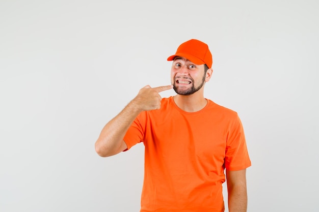 Lieferbote, der in orangefarbenem T-Shirt auf seine Zähne zeigt, Vorderansicht der Kappe.